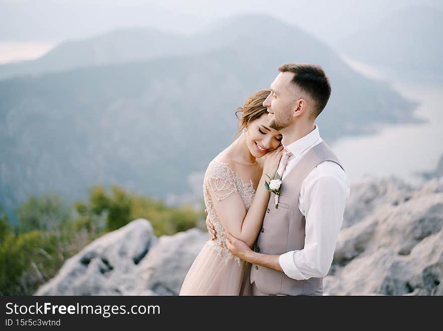 Smiling groom embraces bride on the mountain. Portrait. High quality photo