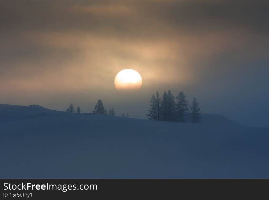 A huge sun peeps through the fog. Fabulous winter landscape in the mountains. Bright winter morning / evening. Minimalism. Winter