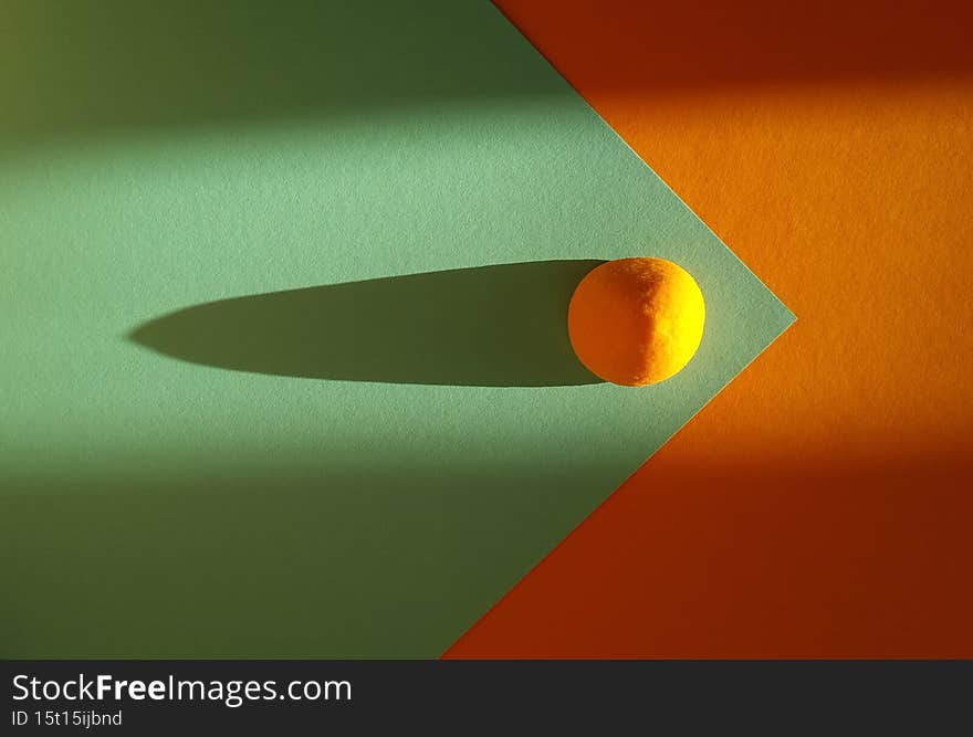 orange spherical candy in the rays of the sun on a turquoise orange background