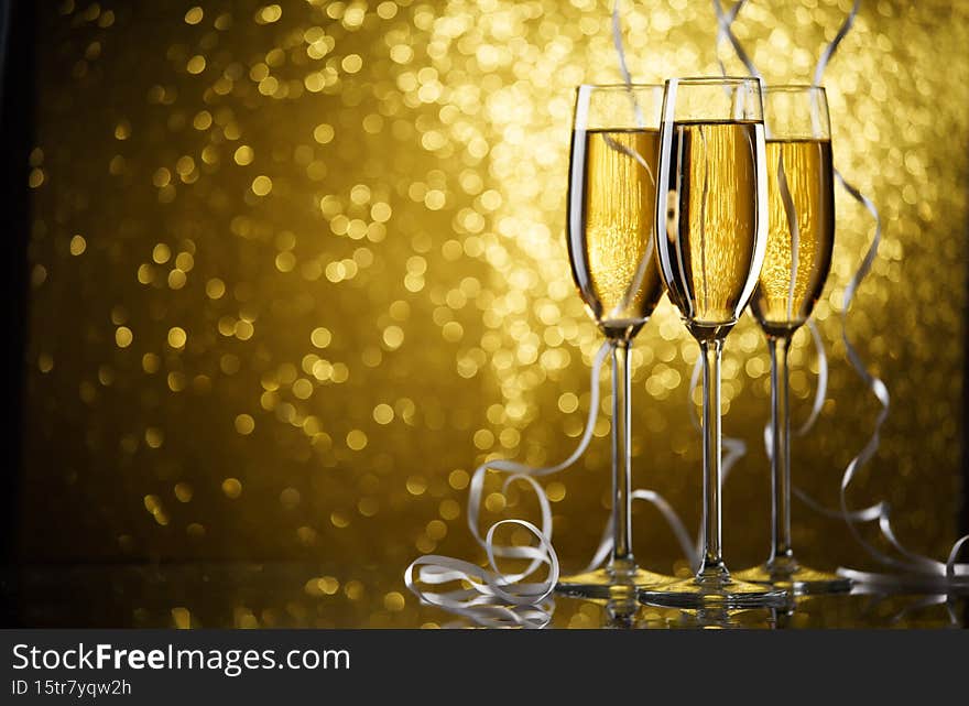 Picture of three glasses with champagne on gold background.