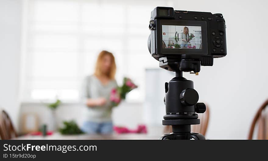 Bokeh photo of florist girl making up bouquet of pink flowers.