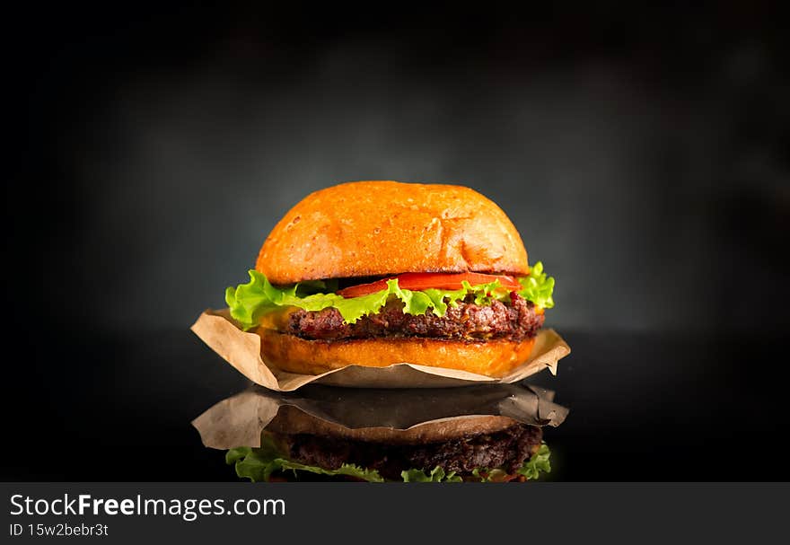 Hamburger over black background on the table. Cheeseburgers on fresh buns with succulent beef and fresh salad