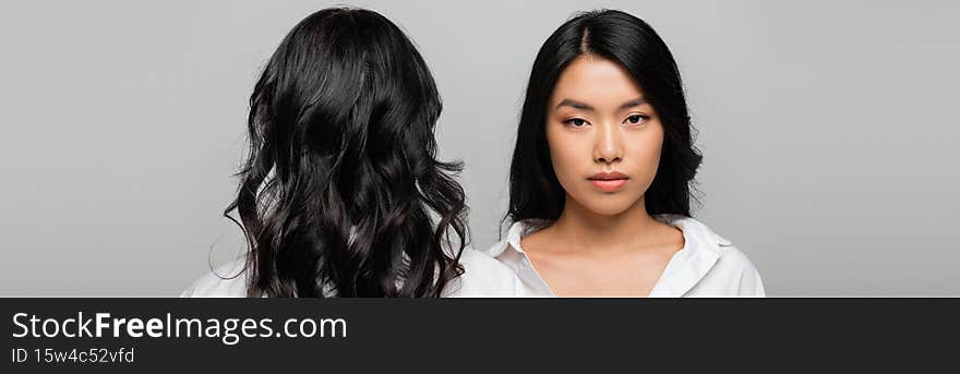 back view of brunette asian mother near young adult daughter  on grey, banner,stock image