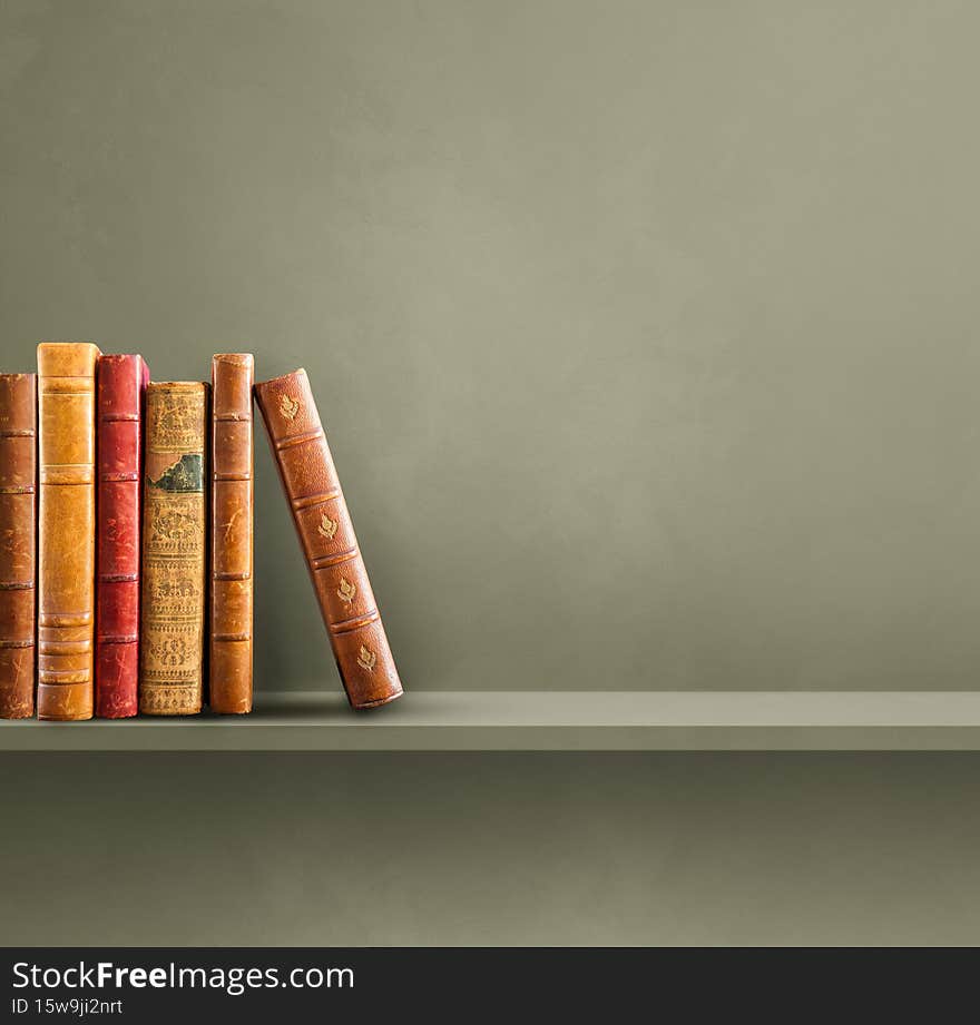 Row of old books on green shelf. Square background