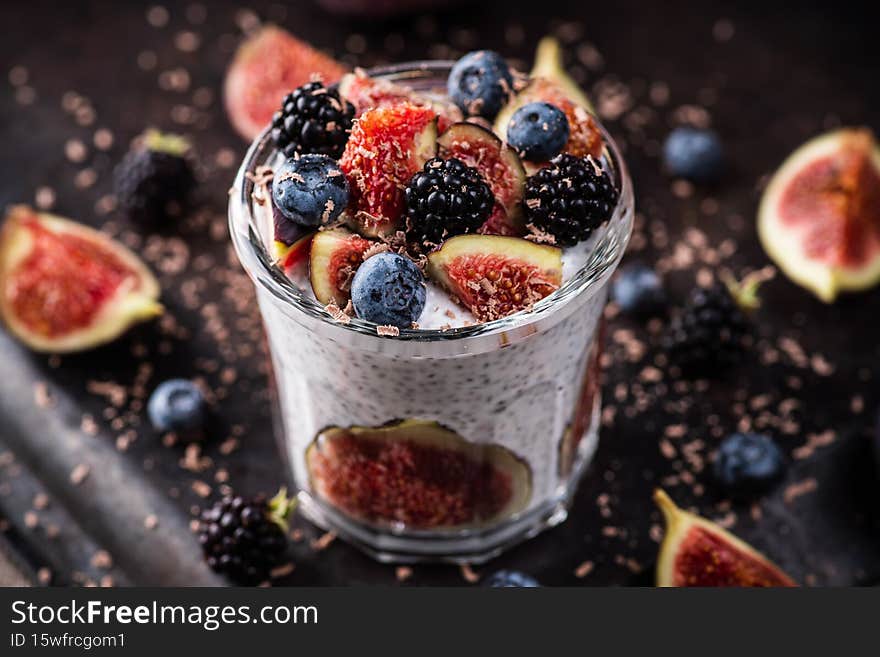 Healthy chia pudding with figs and dark berries in glass on the rustic background. Selective focus. Shallow depth of field