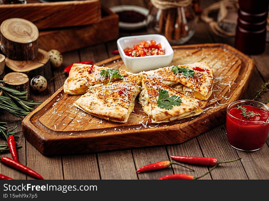 Chicken quesadilla with salsa sauce on wooden serving board