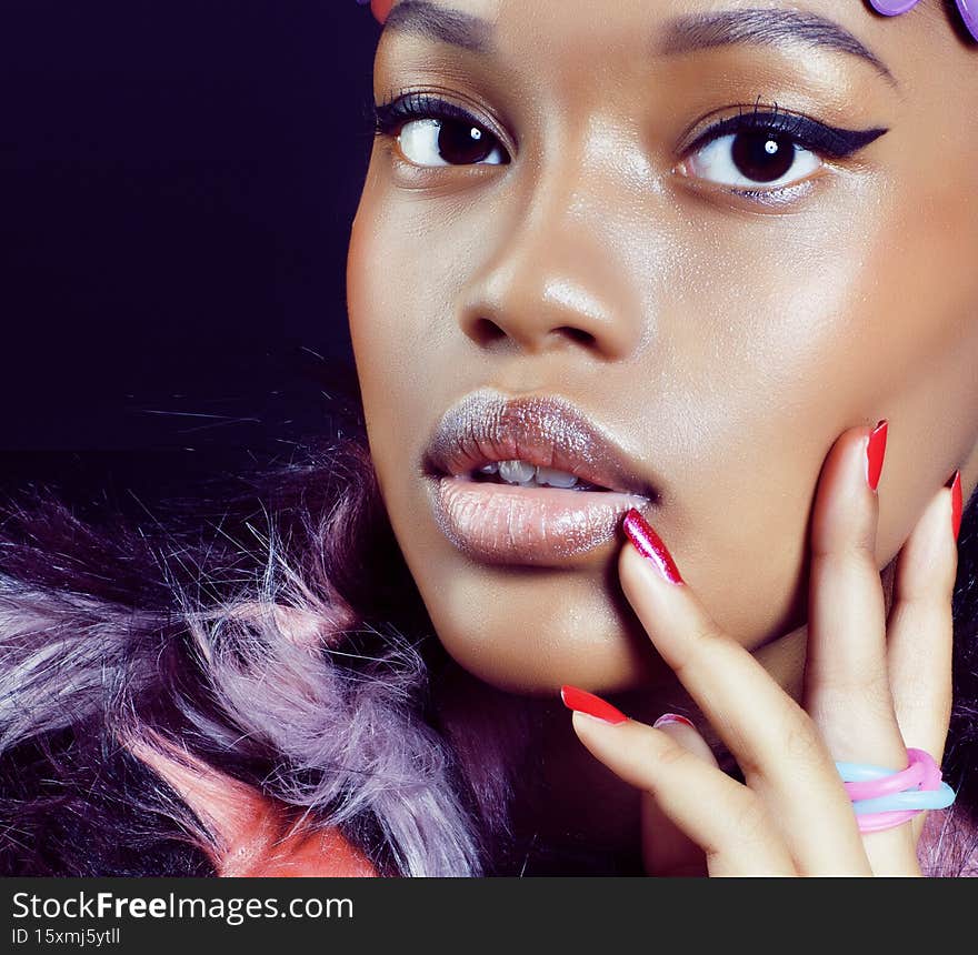 young pretty african american woman in spotted fur coat and flowers on head smiling on black background, fashion people concept close up