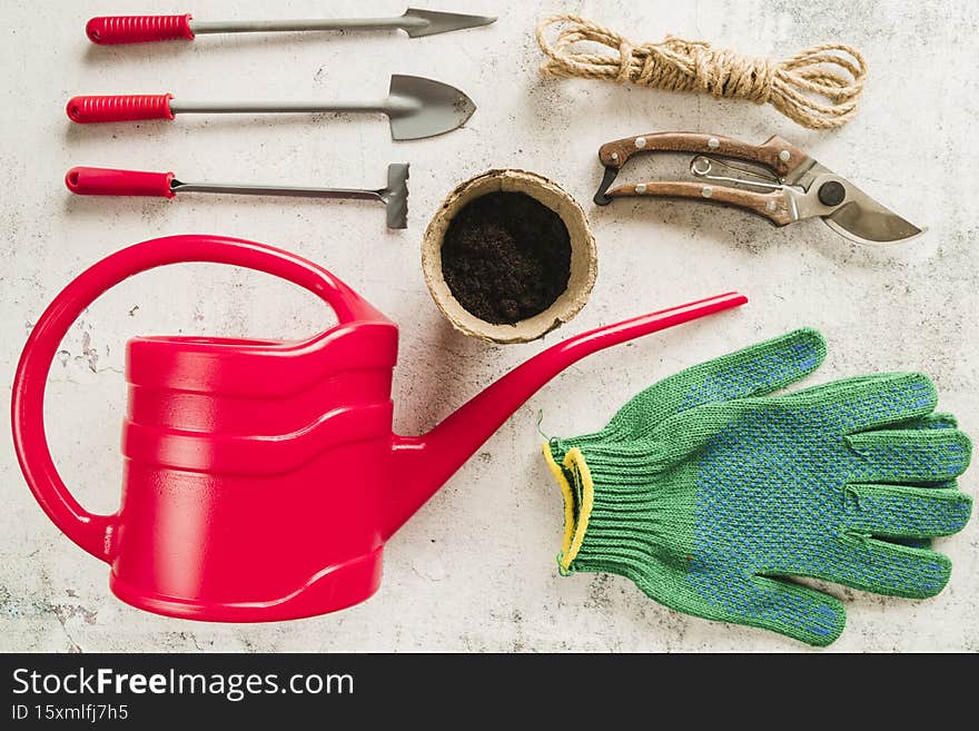 gardening equipment watering can peat pot secateurs rope gardening gloves concrete backdrop. High resolution photo