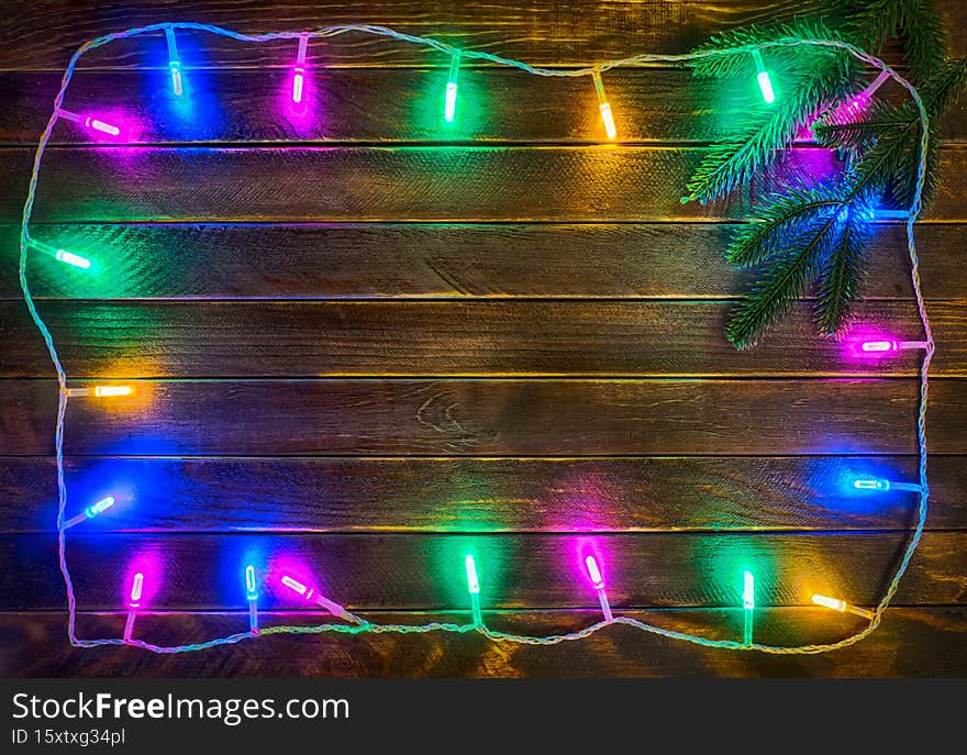 Frame of the christmas electric light garland on the dark wooden background.