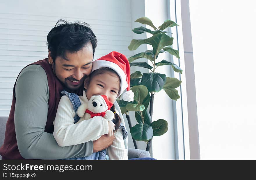 Portrait single handsome asian father and little happy sweet caucasian girl or child smiling together, wearing Santa hat to
