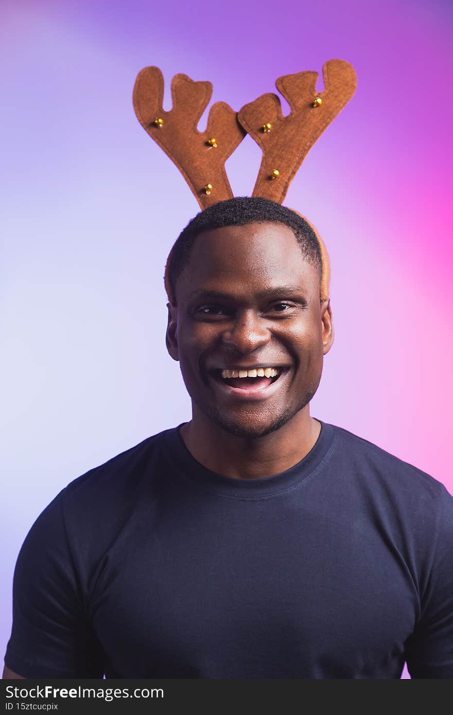 Portrait of african american man wears rudolph deer horns enjoy his accessory for christmas eve party celebration on colourful background.