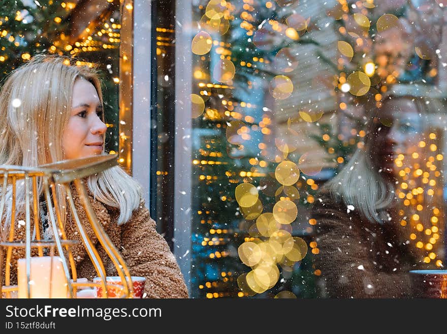 Girl walking in Christmas traditional market decorated with holiday lights in the evening. Winter portrait beautiful
