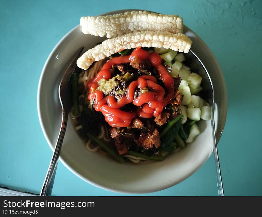 Chicken noodles in a bowl, with chicken pieces and additional sauce and soy sauce