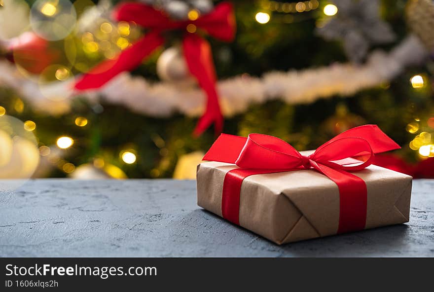 A gift on the background of a Christmas tree. Side view, copy space.
