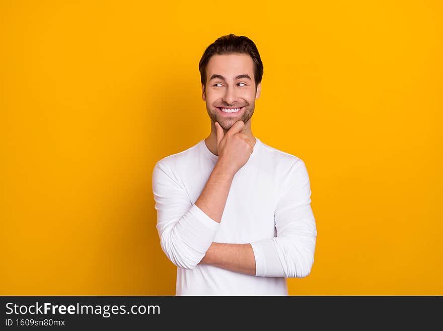 Photo of satisfied funny man arm on chin beaming smile look empty space isolated on yellow color background