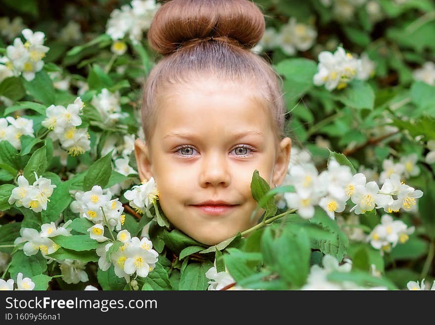Beautiful face of caucasian little girl of 5 years between jasmine bush