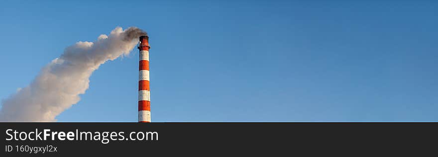 Banner. White thick smoke from the boiler room chimney. Smoke against the blue sky. Air pollution. Heating of the city. Industrial zone. Banner. White thick smoke from the boiler room chimney. Smoke against the blue sky. Air pollution. Heating of the city. Industrial zone.