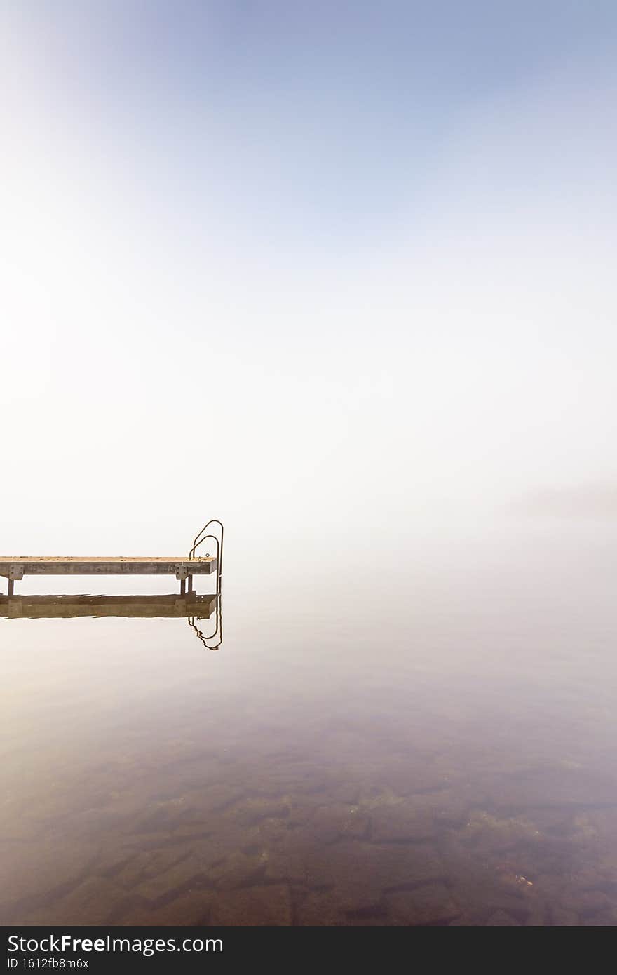 Jetty at calm lake at Alphen aan den Rijn, the Netherlands in morning fog. Jetty at calm lake at Alphen aan den Rijn, the Netherlands in morning fog