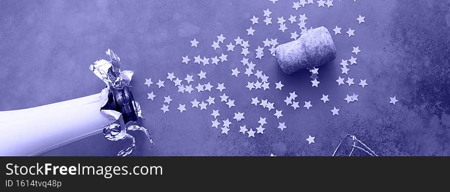 Champagne bottle with confetti stars on dark grey background. New year, birthday, anniversary, or wedding concept