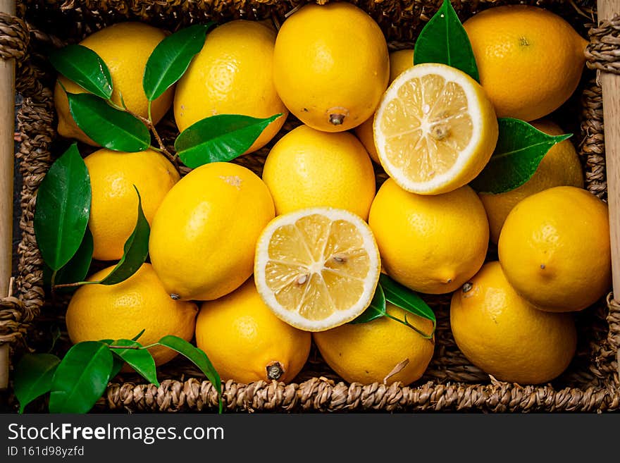 Fresh lemons with foliage in a basket. On a rustic dark background. High quality photo