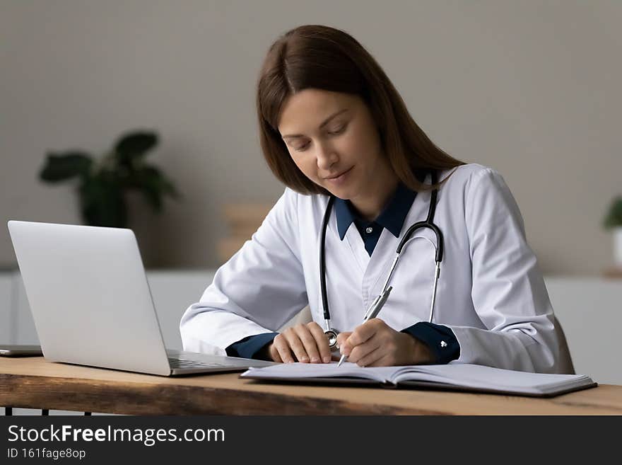 Concentrated young woman medical worker take notes at workplace