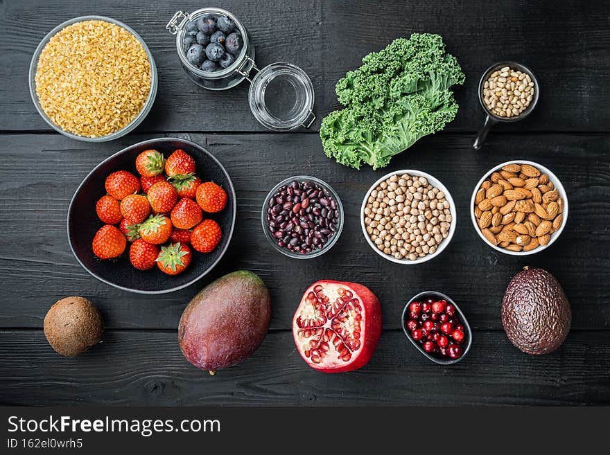 Healthy food and clean eating selection, top view, on black wooden background