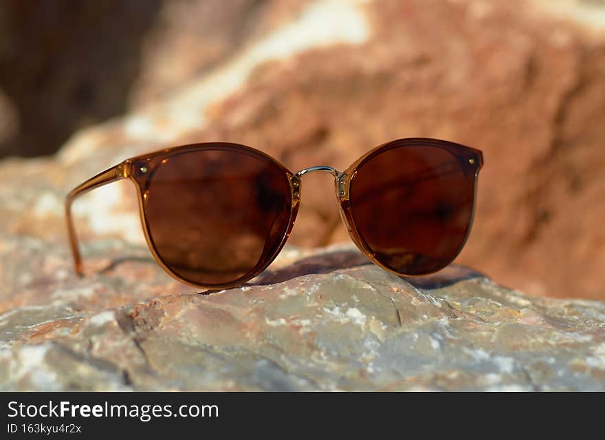 Sunglasses on the beach summer sun stone close-up