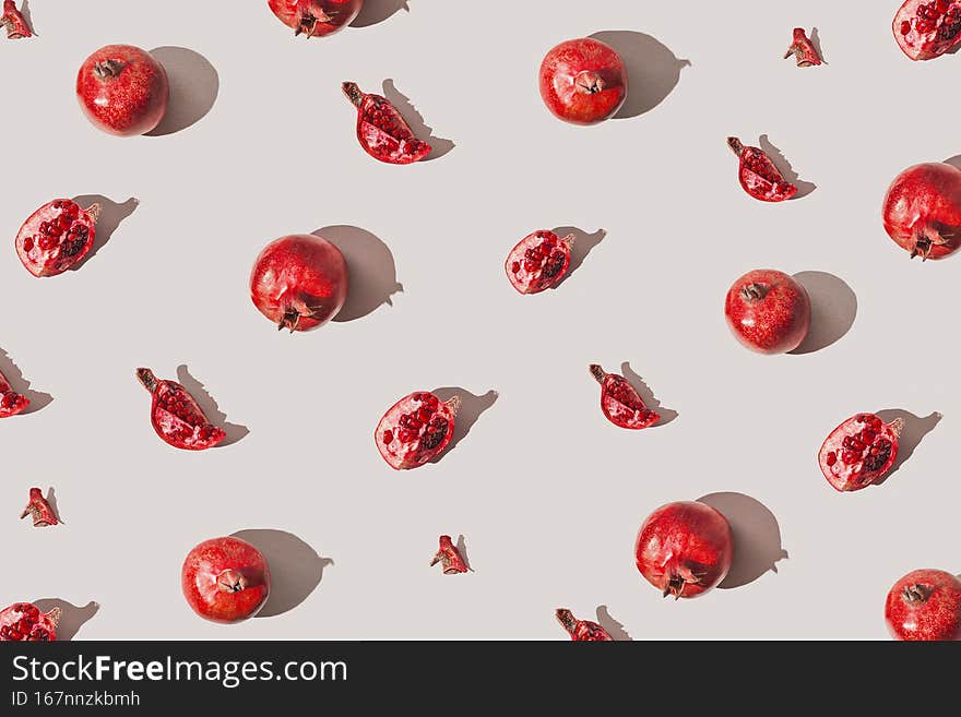 Creative pattern made of fresh pomegranates on pastel grey background with sunlit. Minimal style. Top view. Flat lay