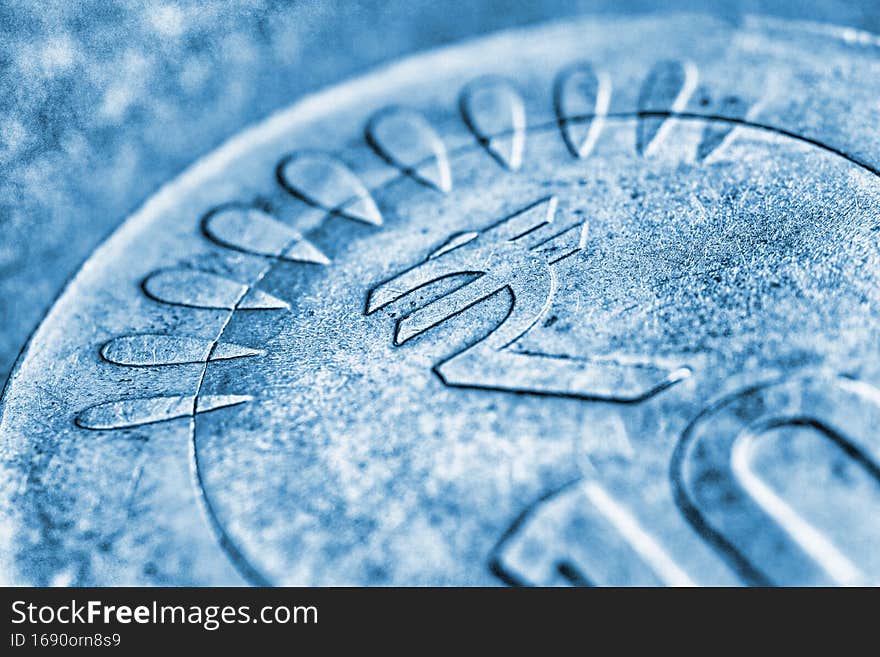 Translation: rupee. Fragment of Indian 10 rupee coin with the sign of the national currency close-up. Blue tinted background from money about economy or finances of India. Macro