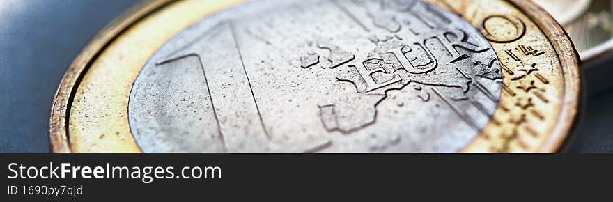 Euro coins. The focus is on the inscription with the name of the Euro Zone currency on the 1 euro coin. Closeup. Banner about the economy and money of the European Union. Macro