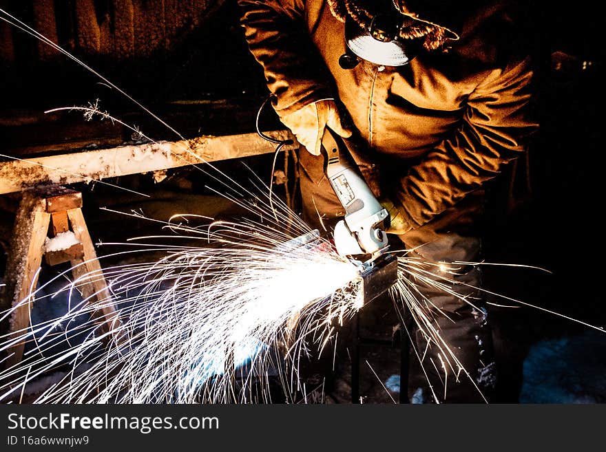 Worker grinding metal with sparks flying