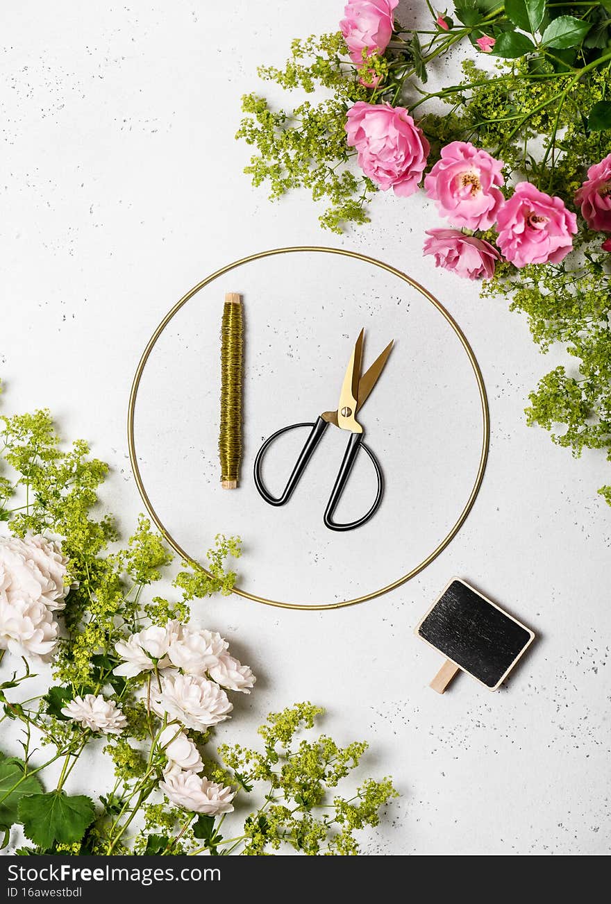 Top view of workplace with pink and white rose flowers, green lady`s mantle blossom and tools to create a flower wreath. Decorative home handmade concept. Step 1