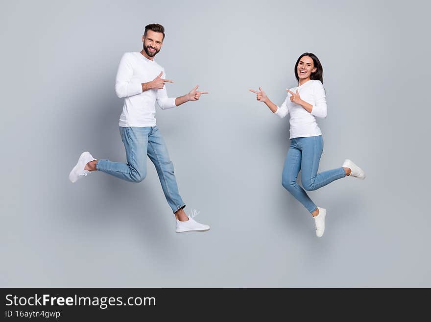 Full body photo of cute young brunet couple jump index wear white shirt jeans footwear isolated on grey background.