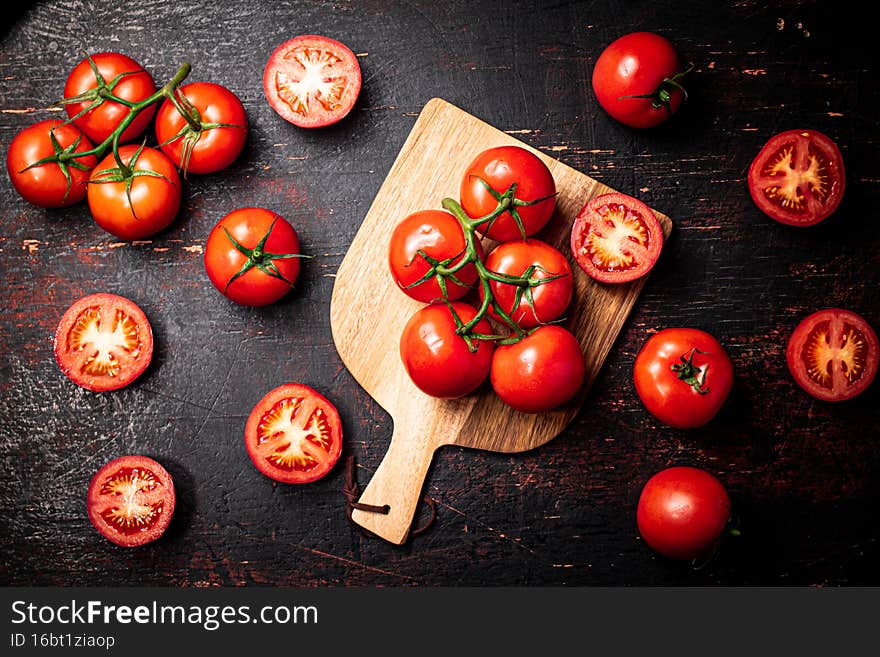 Fresh tomatoes on a wooden cutting board. Against a dark background. High quality photo