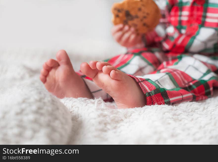 Children's feet on bed in Christmas pajamas close-up.