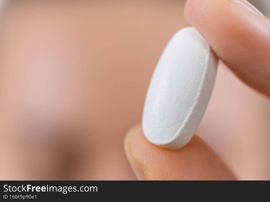 macro photo of hand holding white pill. medical capsule, supplement or antibiotic, pharmaceutical concept