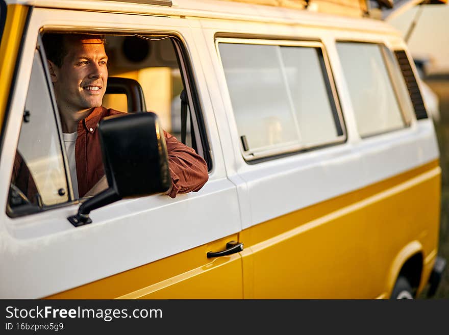 smiling happy man on road trip driving yellow van. Smiling male travelling by van