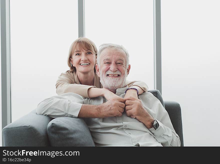 Portrait of senior elderly couple in casual outfit sitting on couch and cuddle together with happy and romantic emotion in living room. Portrait of senior elderly couple in casual outfit sitting on couch and cuddle together with happy and romantic emotion in living room