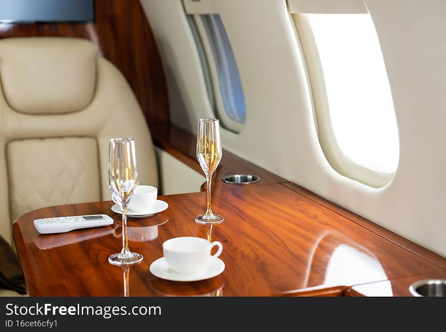 Interior of a business class of a commercial passenger plane, an armchair and a window, a table and a cocktail glass