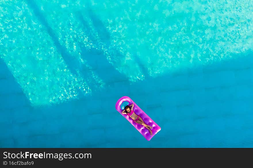 little girl floats on an inflatable mattress in the pool