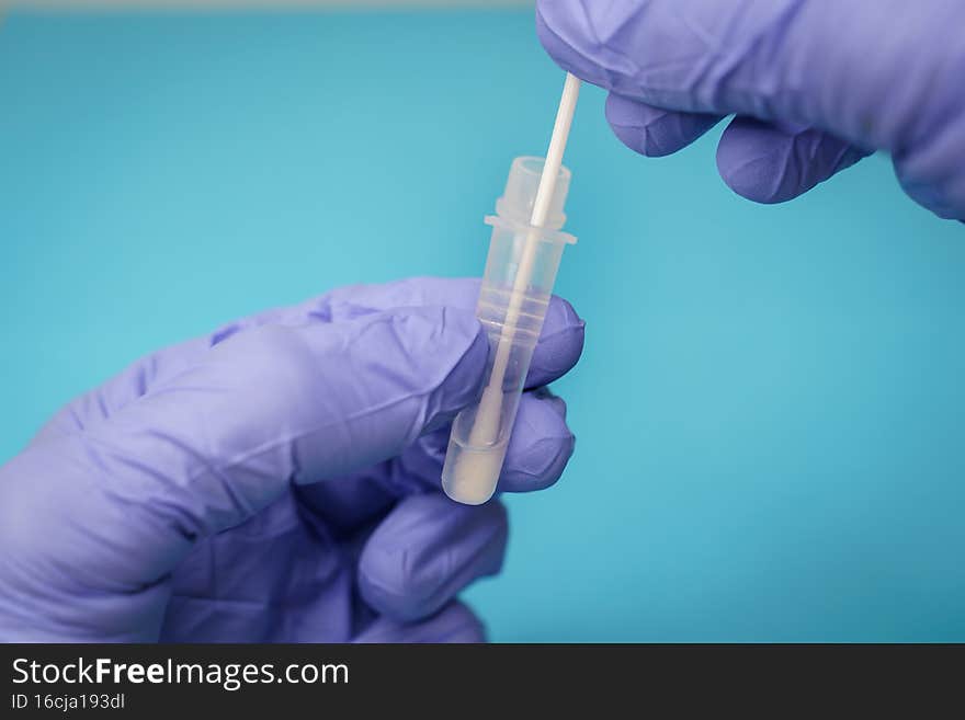 Doctor or nurse inserting a swab with a patient sample into a extraction tube, in the process of an COVID antigen detection rapid diagnostic test or RDT. Doctor or nurse inserting a swab with a patient sample into a extraction tube, in the process of an COVID antigen detection rapid diagnostic test or RDT.