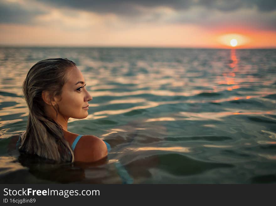 A girl with beautiful facial features looks into an unknown distance while sitting in the estuary
