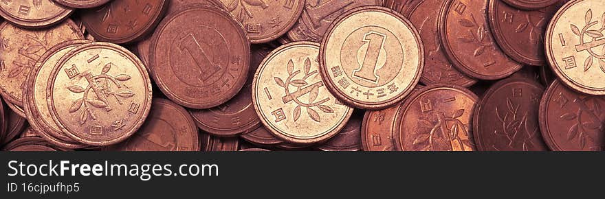 Surface of Japanese 1 yen coins. Scratched money from circulation. Close-up. Red tinted banner on the theme of the economy finance or banks in Japan. Macro