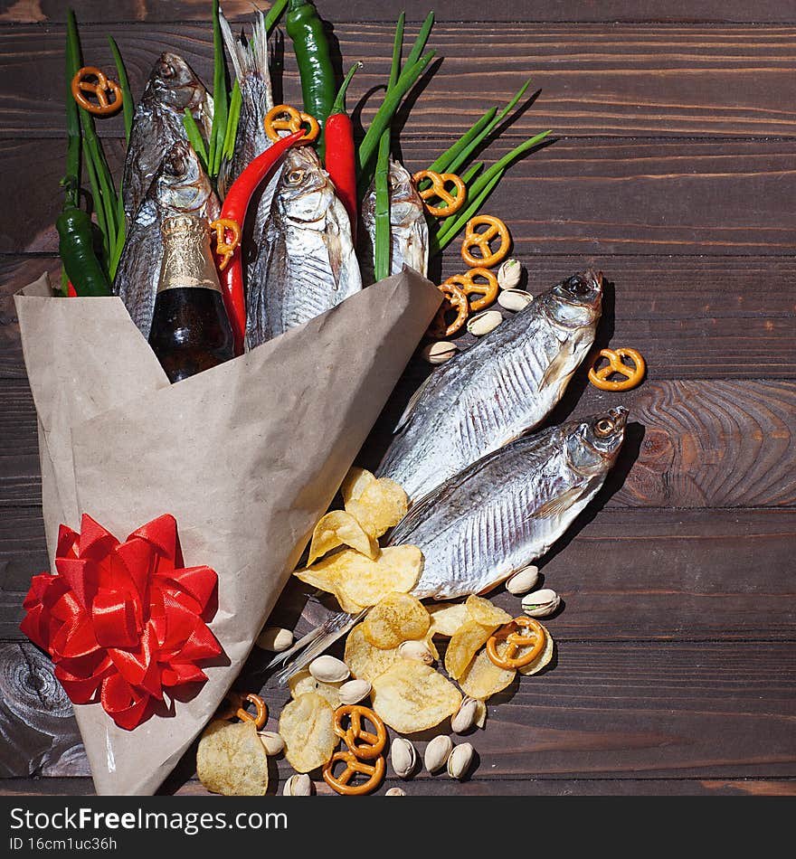February 23. Gift for men. A bouquet of dry fish, chips, pistachios, green onions, chili peppers. Decorated with a red bow. Men`s Day of Defenders of the Fatherland in Russia, Belarus, Tajikistan, Kyrgyzstan. Copyspace. Selective focus.