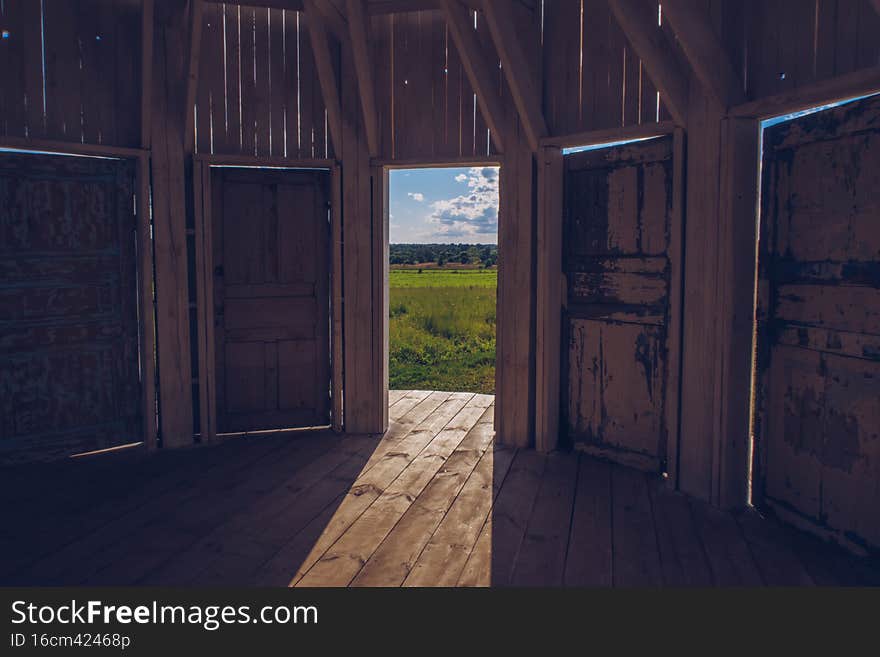 Kaluga region, Russia - July 2020: Inside white wooden Rotunda building with many doors with a view to a green meadow grass field