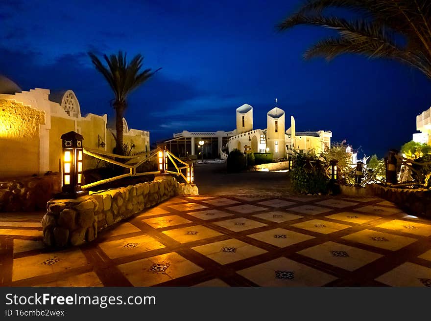 Calm serene of oriental houses, palm trees at night with bright lanterns. Vacation concept. High quality photo