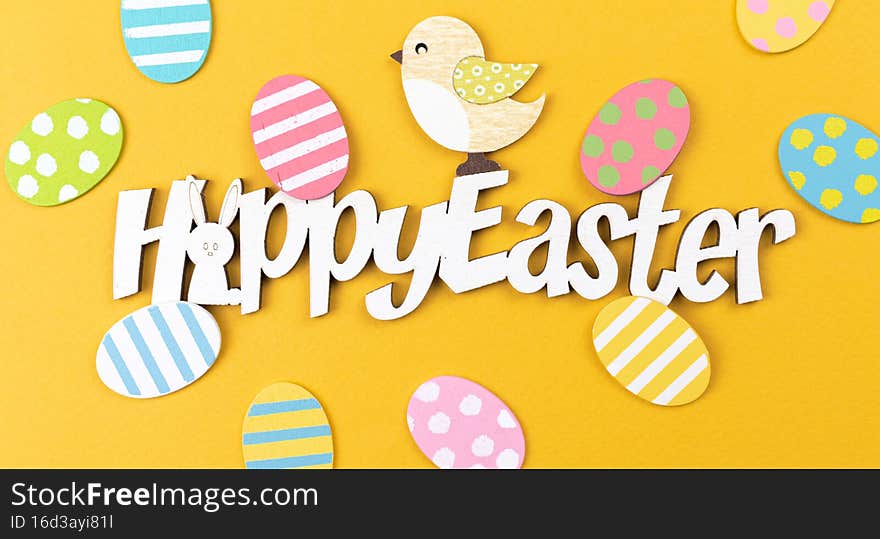 Happy Easter greeting card concept with text and decorations. Spring holiday yellow background, flat lay and top view