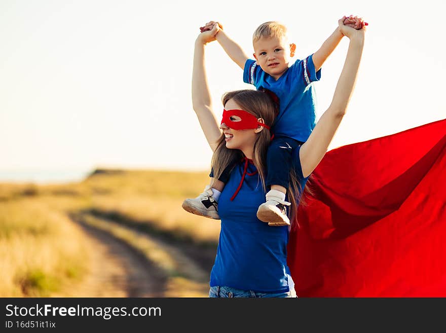 Mom and son play superheroes, Happy mom holds a small child in her arms, simulate flight, pretend to be real superheroes