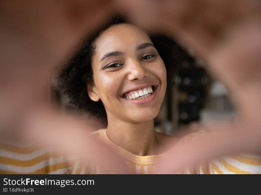 Close up joyful young African American woman making heart sign.