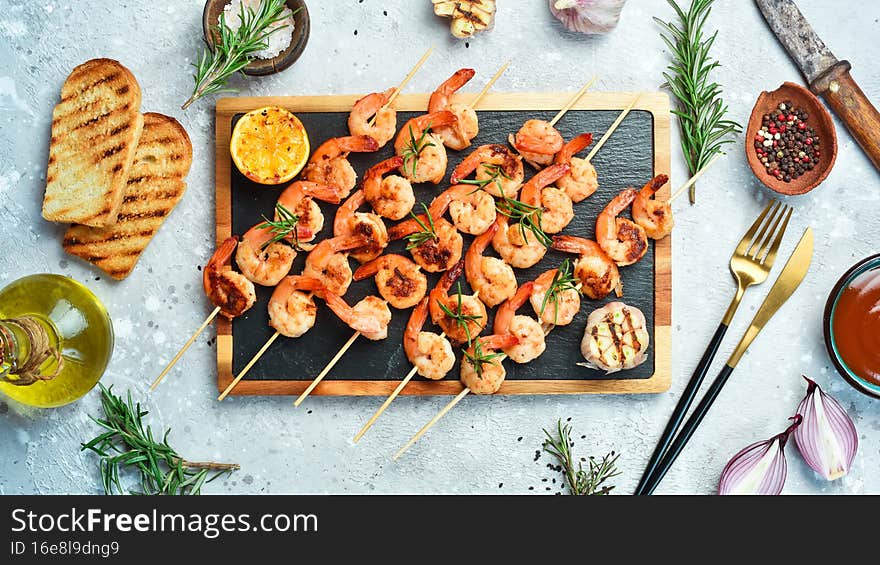 Shrimp for barbecue. Grilled shrimps on skewers with lemon and garlic. Seafood. On a stone background